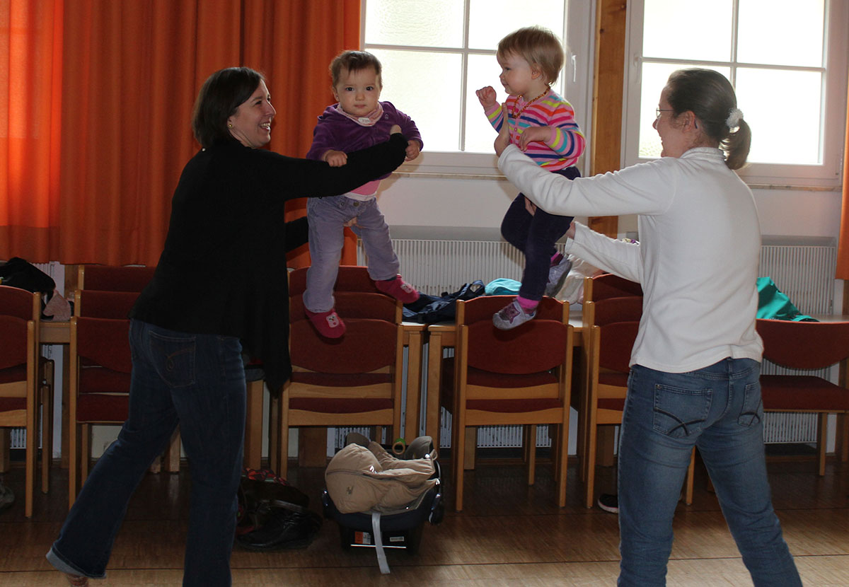 Musikgarten, zwei Mütter, die ihre Babys im Tanz in die Luft heben