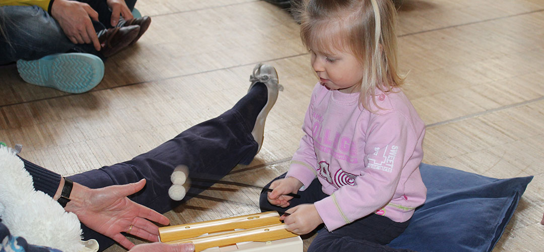 Slide03 Musikgarten, Kind spielt auf einem Orff-Instrument